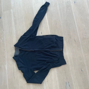 Svart kofta med dragkedja - Säljer en stilren svart kofta med dragkedja framtill. Perfekt för lager-på-lager under höst och vår. Den har en enkel design med långa ärmar och är gjord i ett mjukt material som känns skönt mot huden.