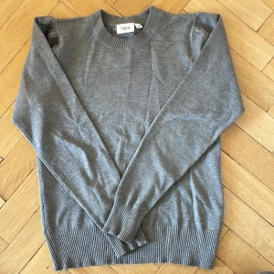Grå tjocktröja  - Grå tjocktröja med lite puffiga axlar.