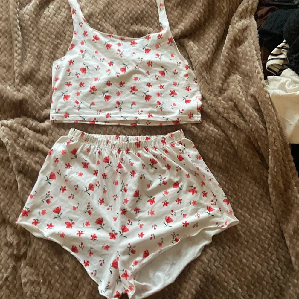 Vitt pyjamas set med röd/rosa blommor , finns ingen lapp men passar som M. Muu.
