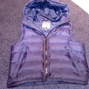 Blå väst - Säljer en snygg blå dunväst från Lee Cooper. Västen har en dragkedja framtill och en mysig huva. Perfekt för kyliga dagar och passar bra till både höst och vår. Den är i bra skick och redo för nya äventyr! 🧥💙