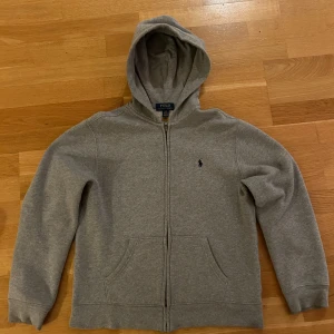 Polo Ralph Lauren storlek 14-16 - Grå Ralph Lauren Ziphoodie i storlek 14-16. Tröjan är liten i storleken, passar 152-158.     