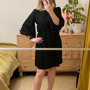 River Island svart klänning storlek S - Svart klänning med puffärmar och rund halsringning. Klänningen har en rak passform och är tillverkad i ett mjukt och bekvämt material.  Säjles utan rem  Samfraktar gärna