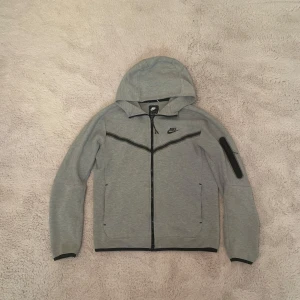 Nike tech fleece - En grå Nike tech fleece storlek S. Den är ganska använd så man ser på bilderna att det är lite slitage men det är inga större fel på den som märks. Självklart äkta, byxor finns o köpa separat tockså.