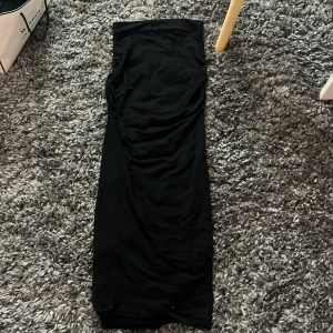 Kjol - Svart kjol med detaljer på sidorna, aldrig använt då ja tycker den är svår att gå i. Jag är 157cm och den sitter precis vid marken