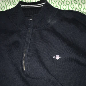 Svart tröja med dragkedja från GANT - Snygg svart tröja från GANT med dragkedja och ribbad krage. Tröjan har en diskret logga på bröstet och vita ränder på insidan av kragen. Perfekt för en stilren look. Säljer den då den är för liten för mig! Tröjan tvättas såklart innan frakt!  Priset kan diskuteras vid snabb affär. 