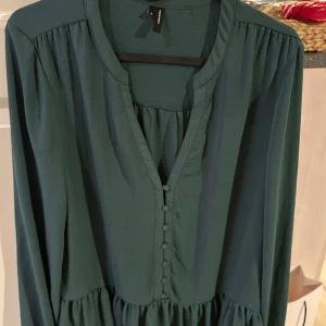 Grön blus från Vero Moda - Snygg grön blus från Vero Moda med långa ärmar och knappar framtill. Perfekt för en stilren look. 💚