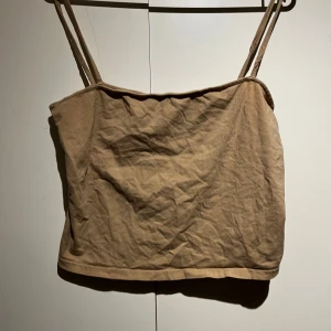 Beige topp med smala axelband  - Säljer en stilren beige  topp med smala axelband. Perfekt för varma sommardagar eller som ett basplagg i garderoben.