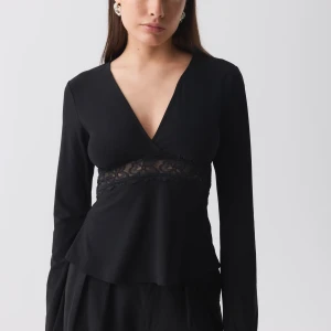 Lace detail topp -  svart topp med v-ringning och spetsdetalj i midjan. Aldrig använd då den är för stor  