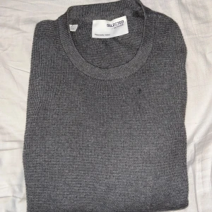 Grå tröja från Selected Homme - Säljer en stilren grå tröja från Selected Homme. Tröjan är långärmad och tillverkad i ett mjukt material som passar perfekt för kyligare dagar. Enkel och klassisk design som funkar till det mesta. Perfekt för dig som gillar en tidlös look.