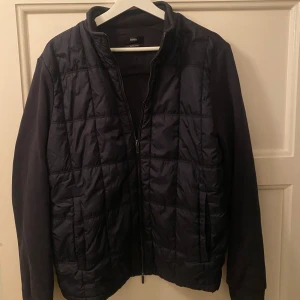 Mörkblå Cardigan - Snygg mörkblå  Cardigan-jacka från BOSS med dragkedja framtill. Jackan har långa ärmar och en stilren design som passar perfekt för kyligare dagar. Perfekt för dig som vill ha en stilren look. Står storlek XL i den men den absolut snarare en M. Jag är 191 CM på bilden. Passa perfekt om man är 179-187 CM. Den är som nyskick. Nypris 1499ke