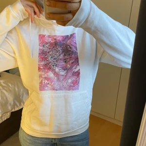 Vit hoodie med rosa tryck - Säljer en vit hoodie med ett unikt rosa tryck på framsidan. Hoodien är ifrån the cool elephant. Knappt använd i jättebra skick och storlek S.
