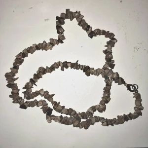 Brunt halsband med stenar - Unikt halsband med bruna stenar i oregelbundna former. Perfekt för att ge en naturlig touch till din stil. Halsbandet har en enkel låsning och är lätt att bära.
