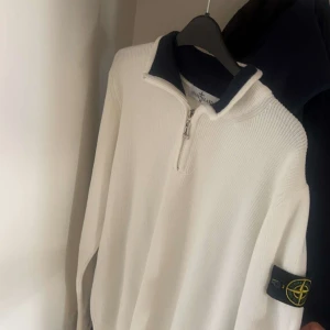 vit stone island tröja - Säljer en stilren vit tröja från Stone Island med dragkedja och lång ärm. Tröjan har en mörkblå krage och det ikoniska märket på ärmen. Perfekt för en avslappnad och trendig look. pris kan diskuteras i princip i ny skick 