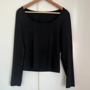 Svart långärmad topp - Snygg svart långärmad topp med rund halsringning. Perfekt för en stilren look och kan matchas med olika outfits. Enkel design som passar till många tillfällen.