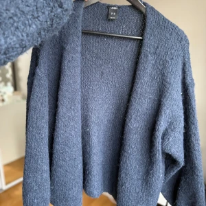 Mörkblå kofta från Lindex - Säljer en mysig mörkblå kofta från Lindex. Perfekt för kyliga dagar med sin stickade design. Koftan har en öppen front och långa ärmar, vilket gör den lätt att slänga på över en t-shirt eller blus.