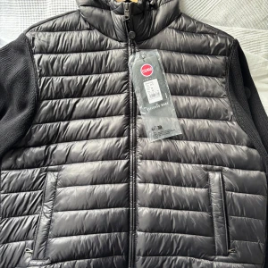 Svart pufferjacka från Colmar / Cardigan  - Säljer en snygg svart pufferjacka från Colmar. Som är helt ny med prislapp. Jackan har en quiltad design med dragkedja framtill och två praktiska fickor. Ärmarna är stickade vilket ger en cool kontrast till den glansiga ytan. Perfekt för kyligare dagar! Ny pris är 3600kr!!!!