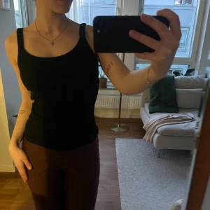 Svart linne  - Svart, ribbat linne från Gina Tricot. Toppen har lite bredare axelband och en klassisk rund halsringning