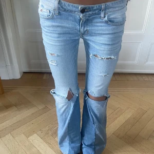 Ljusblå low waist bootcut jeans med slitningar - Snygga ljusblå bootcut jeans med coola slitningar!! De är omsydda från hollister. Köptes för 700 på plick men aldrig använda av mig ❣️midja: 37cm och innerbenslängd: 73cm ❤️
