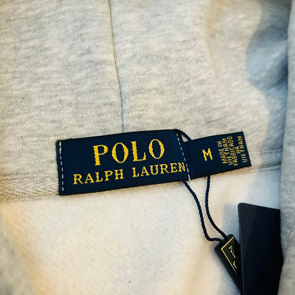Säljer en stilren grå hoodie från Polo Ralph Lauren med dragkedja och klassisk logga på bröstet. Tröjan har långa ärmar och en praktisk huva med snören. Perfekt för en avslappnad look.. Neuletakit & Villapaidat.