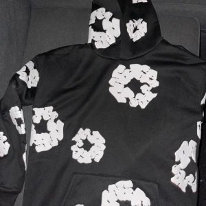 Svart hoodie med vitt mönster och den heter Denim tears tracksuit - Säljer en svart hoodie med ett unikt vitt mönster. Tröjan har en klassisk passform med huva och långa ärmar. Perfekt för en avslappnad stil.   Det finns sånna som prickar på byxorna  tröjan e bara använda 3 gånger annars helt ny små prickar finns bara på byxorna inte tröjan 