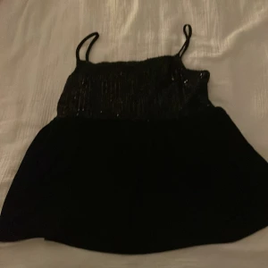 Svart paljettlinne från Gina Tricot - Snyggt svart linne från Gina Tricot med glittrande paljetter på överdelen. Linnet har smala axelband och en enkel design som passar perfekt för en kväll ute. Perfekt för att lägga till lite glamour i garderoben! Använd ändats 1 gång!❤️