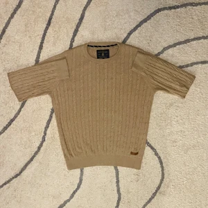Beige kavelstickad bondelid - Säljer en snygg beige stickad tröja från Bondelid. Tröjan har ett klassiskt flätmönster, perfekt för en stilren look. Den har en rund halsringning och en liten läderdetalj vid nederkanten. Passar perfekt för både höst och vår. Pris kan diskuteras 🤝