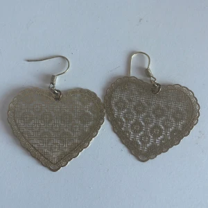 Hjärtformade örhängen i guld - Snygga hjärtformade örhängen i guld med ett intrikat mönster. Perfekta för att ge en romantisk touch till din stil. De är lätta och bekväma att bära hela dagen.