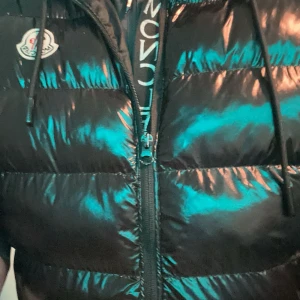  Moncler väst  - Säljer en snygg svart pufferväst från Moncler. Den är quiltad och har en dragkedja framtill. Jackan är perfekt för vintern och håller dig varm och stilren. obs lite sönder vid fickan och när man stänger den öppnas den igen 