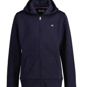 Mörkblå huvtröja med dragkedja - Säljer en snygg mörkblå huvtröja med dragkedja framtill. Perfekt för en avslappnad stil och passar bra till både vardag och träning. Tröjan har en liten logga på bröstet och praktiska fickor. Den är långärmad och gjord i ett mjukt material.