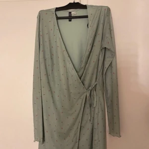 Blommig klänning - Klänning från H&M, använd 1-2 gånger. grön med blommigt mönster. skönt och behagligt tyg. knytning framtill. 