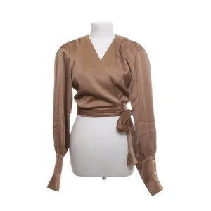 Adoore blus/topp - Topp från Adoore med omlottknyt design. Blusen är brun i satin material med axelvaddar. Nyskick!