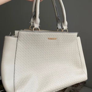 Hanväska  - Jättefin Hanväska i en ljus grå/beige färg:) får plats med det mesta men den kommer med några defekter. Lite trådar sticker ut här och där och den är lite missfärgad på både undersidan och i innerfacken 