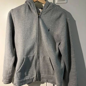 Ralph Lauren Zip hoodie - Säljer denna Ralph Lauren hoodie eftersom den är för stor och inte används. Den har endast blivit använd ca 2 gånger. Skick 9/10. Storleken är XL i barn men motsvarar typ S