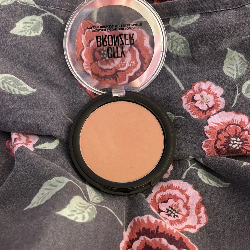 Säljer en Maybelline City Bronzer i nyansen Light-Warm 150. Perfekt för att skapa en naturligt solkysst look med en mjuk kontur. Den kommer i en praktisk rund förpackning med ett genomskinligt lock, så du enkelt kan se färgen. Superenkel att applicera för en fräsch och varm glöd!. Skönhet.