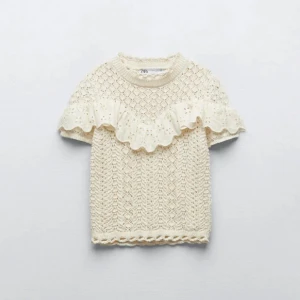 Beige stickad topp från Zara - Superfin beige stickad topp från Zara med korta ärmar och en söt volangdetalj över bröstet. Den har ett vackert mönster och är riktigt bekväm att ha på sig. Passar både till vardags och festliga tillfällen. 🌼