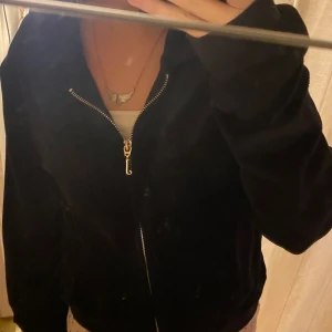 Juicy Couture tröja - Säljer en snygg svart jacka från Juicy Couture. Den har en dragkedja framtill och ett broderat 'J' på ärmen. Perfekt för en casual look! inga defekter(nypris:800kr)