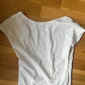 Vit topp  - Med urringning. Lite boatneck. Basplagg
