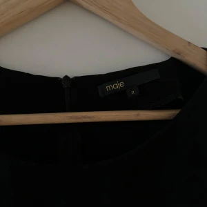 Svart klänning från Maje - Säljer en elegant svart klänning från Maje. Den har en klassisk design med korta ärmar och en rund halsringning. Perfekt för både vardag och festliga tillfällen. Klänningen är i bra skick och redo för en ny ägare!