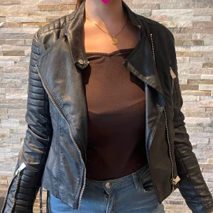 Svart skinnjacka  - Svart skinnjacka med silver detaljer med fin passform i storlek 40, väldigt mode nu med dessa vintage skinnjackor. 