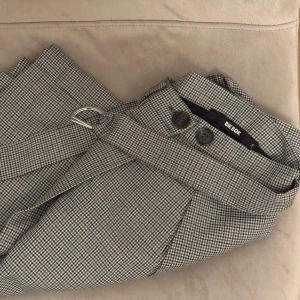 Grå rutig kjol  - Säljer en superfin grå rutig kjol från Bikbok. Den har en omlott-design med knappar och ett bälte i midjan som ger en snygg passform. Storlek S 🤍