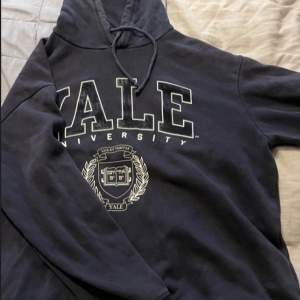 Säljer en snygg och bekväm mörkblå hoodie från Yale University. Den har en stor logga på framsidan och en praktisk huva med dragsko. Perfekt för en avslappnad stil eller för att visa upp din kärlek till Yale!