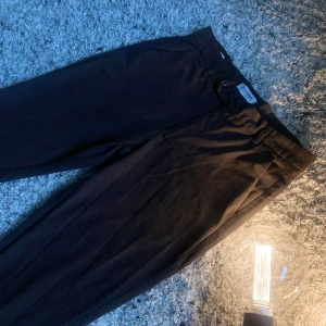 Bruna byxor från Jack & Jones - Säljer ett par snygga bruna byxor från Jack & Jones. De har en klassisk design med knappar och en stilren look. Perfekta för både vardag och lite mer uppklädda tillfällen. Byxorna är i bra skick och redo för en ny ägare! 