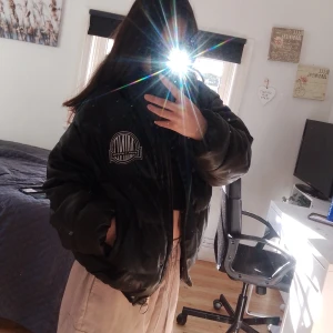Svart pufferjacka från FB Sister - Säljer en snygg svart pufferjacka från FB Sister. Den är i storlek S och har en cool logga på bröstet. Jackan är perfekt för kyligare dagar och har en skön, vadderad känsla. Den har långa ärmar och en dragkedja framtill. Passar perfekt till vardagen 