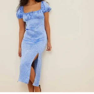 Klänning - Blå/blommig klänning från Sanna Jörnviks kollektion med NA-KD. Använd 2 ggr och är i skick som ny.