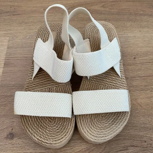 Beige sandaler med kilklack - Snygga och bekväma beige sandaler med kilklack. De har en flätad sula och breda remmar i textil som ger ett stilrent intryck. Perfekta för sommardagar och passar både till stranden och stan. Aldrig använda innan. 