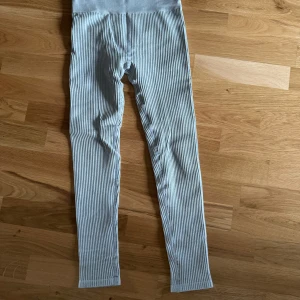 Randiga leggings - Säljer ett par snygga ribbade leggings i grått nyskick. De är superbekväma och har en hög midja som sitter perfekt. Perfekta för både vardag och mysiga hemmakvällar!