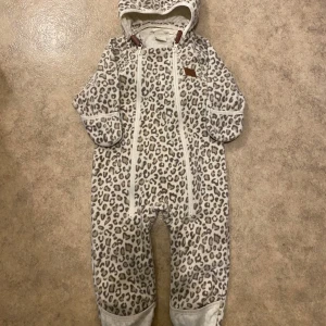 Leopardmönstrad overall från Kuling - Supergullig leopardmönstrad overall från Kuling x Kenza strl 80. Perfekt för de minsta att hålla sig varma i. Overallen har en huva med små öron och dubbla dragkedjor framtill för enkel på- och avklädning. Materialet känns mjukt och mysigt, perfekt 