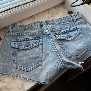 Blå jeansshorts från Pull&Bear - Säljer ett par snygga blå jeansshorts från Pull&Bear i storlek S. De har en cool fransig kant och klassiska femficksdetaljer. Perfekta för sommardagar och festivaler! 🕶️