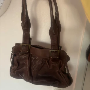Brun axelväska i skinn - Fin brun axelväska i äkta skinn som inte kommer till användning. Väldigt fint skick, inga synliga skador :)