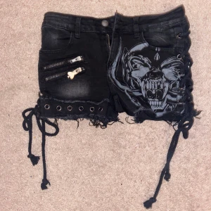 Motörhead Shorts - Grå/svarta Motörhead shorts med snörning längs höfterna.